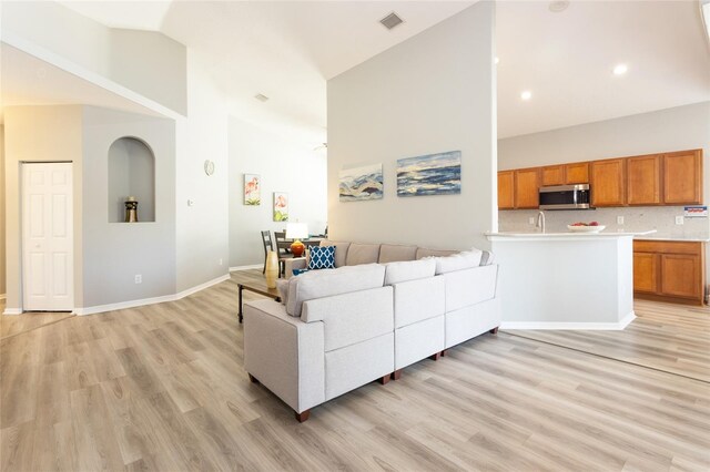 125 Raintree Cir, Palm Coast, FL 32164 - living room featuring light wood-type flooring, baseboards, and high vaulted ceiling