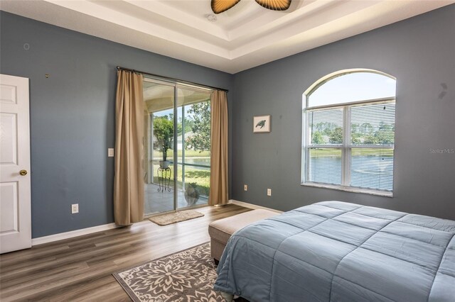 125 Raintree Cir, Palm Coast, FL 32164 - bedroom with baseboards, access to outside, a tray ceiling, and wood finished floors