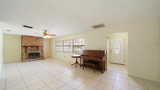 689 16th St, Saint Augustine, FL 32080 - entrance foyer with ceiling fan, a textured ceiling, light tile patterned floors, a brick fireplace, and baseboards