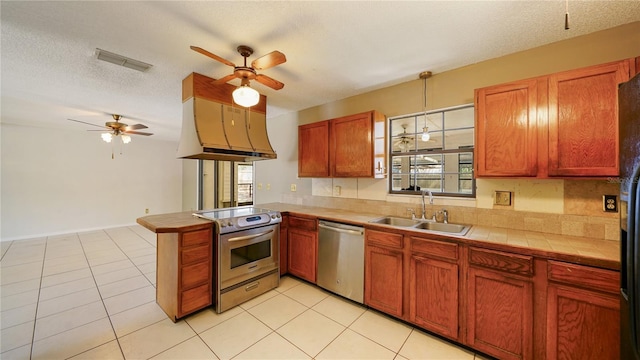 689 16th St, Saint Augustine, FL 32080 - kitchen with stainless steel appliances, a sink, ceiling fan, a peninsula, and tile countertops
