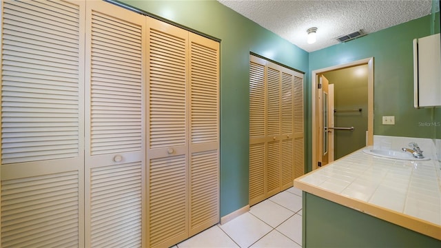 689 16th St, Saint Augustine, FL 32080 - bathroom with a closet, a textured ceiling, tile patterned floors, and vanity