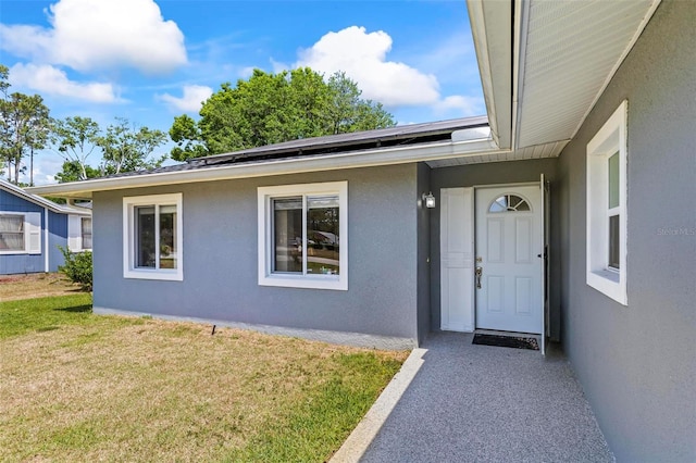 13 Belleaire Dr, Palm Coast, FL 32137 - view of exterior entry featuring stucco siding and a yard