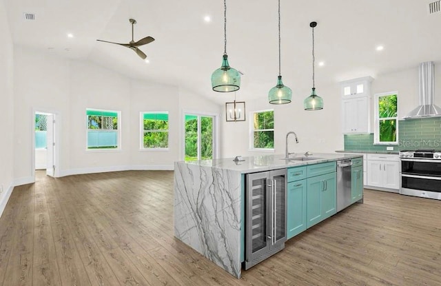 kitchen with appliances with stainless steel finishes, a kitchen island with sink, light wood-style flooring, white cabinetry, and wine cooler