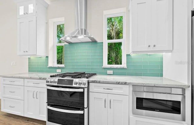 kitchen with white cabinetry, wall chimney range hood, and range with two ovens