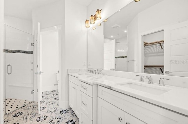bathroom with a sink, a stall shower, and double vanity