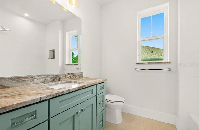 full bathroom with vanity, plenty of natural light, and toilet