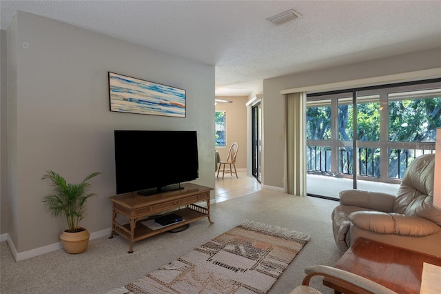carpeted living room featuring visible vents, a textured ceiling, and baseboards