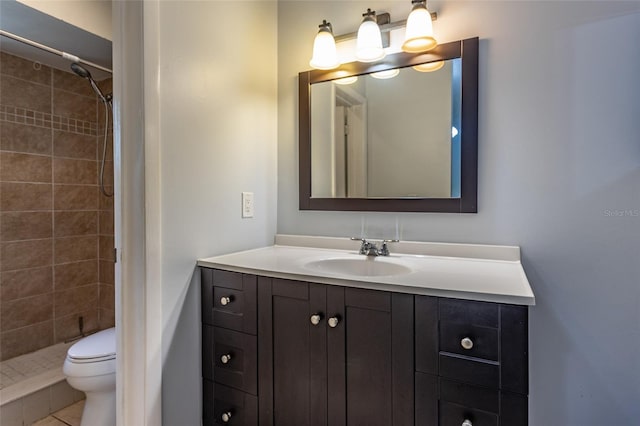 bathroom featuring vanity, a tile shower, and toilet