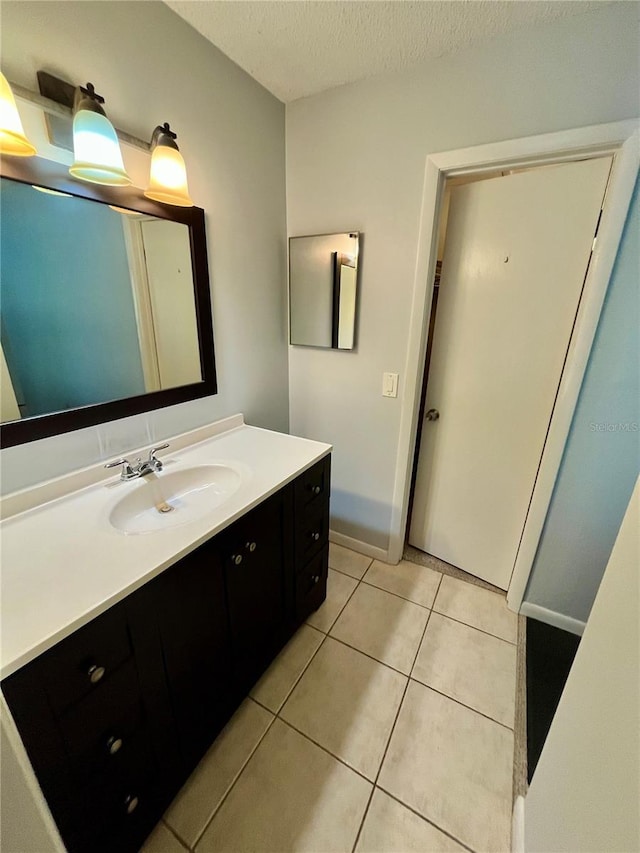 bathroom with a textured ceiling, tile patterned floors, and vanity