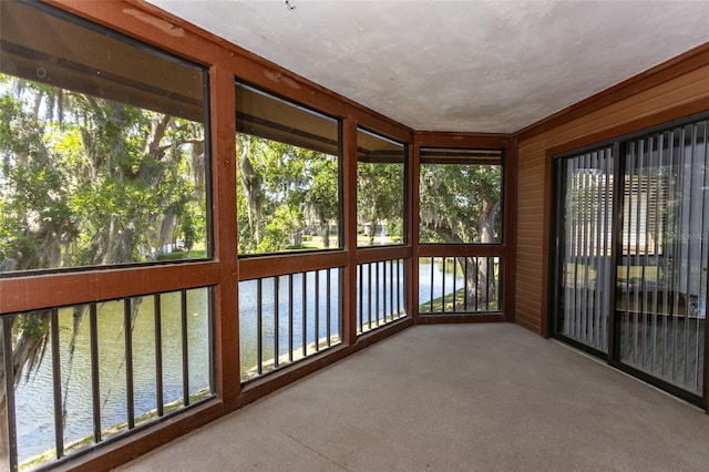 unfurnished sunroom featuring a water view and carpet flooring