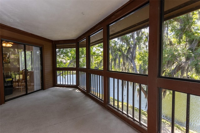 unfurnished sunroom featuring a water view and carpet floors