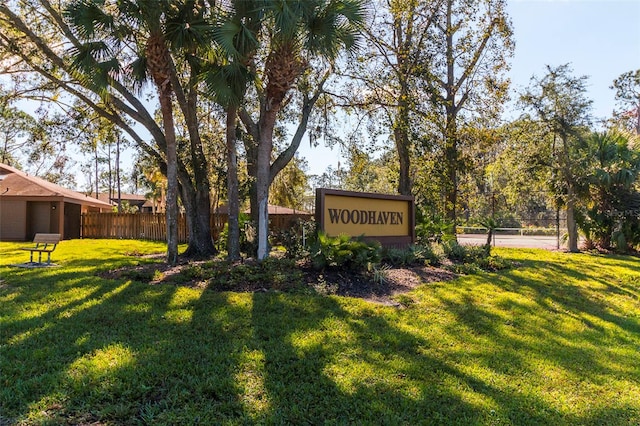 community sign with fence and a yard