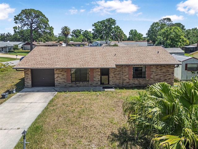 ranch-style home featuring brick siding, a shingled roof, a front lawn, and concrete driveway