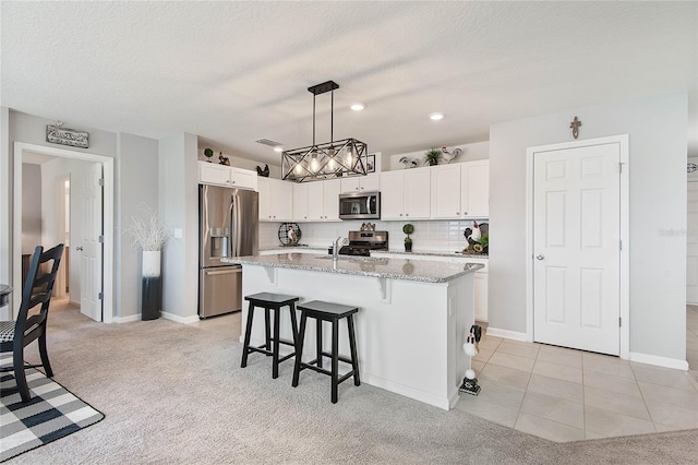 7 Windsor Ter, Palm Coast, FL 32164 - kitchen with white cabinets, light stone countertops, a breakfast bar, a kitchen island with sink, and stainless steel appliances