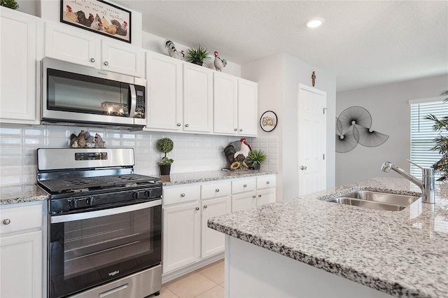 7 Windsor Ter, Palm Coast, FL 32164 - kitchen with decorative backsplash, white cabinets, light stone counters, a sink, and appliances with stainless steel finishes
