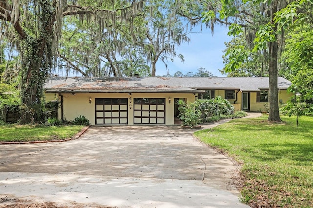 ranch-style home featuring a garage, stucco siding, driveway, and a front lawn