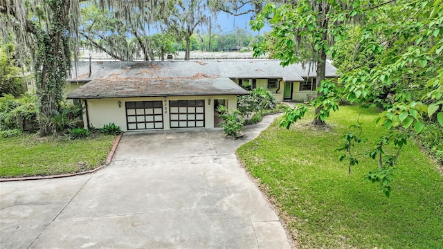 view of front facade with stucco siding, concrete driveway, and a front lawn
