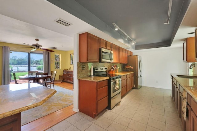 kitchen featuring visible vents, baseboards, rail lighting, a sink, and stainless steel appliances