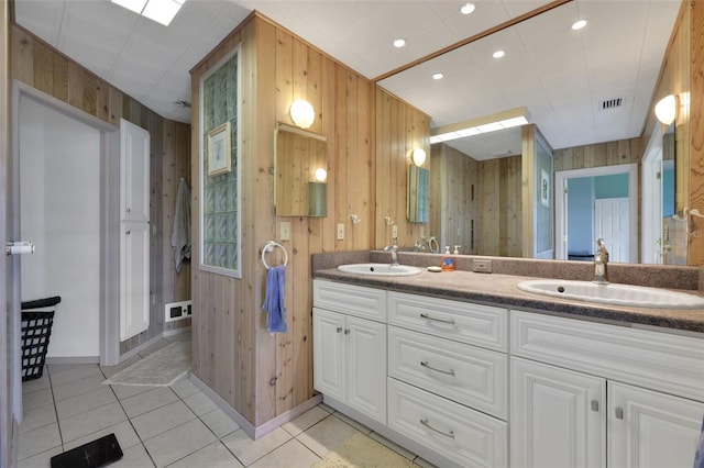 full bath with a sink, baseboards, tile patterned flooring, and wood walls