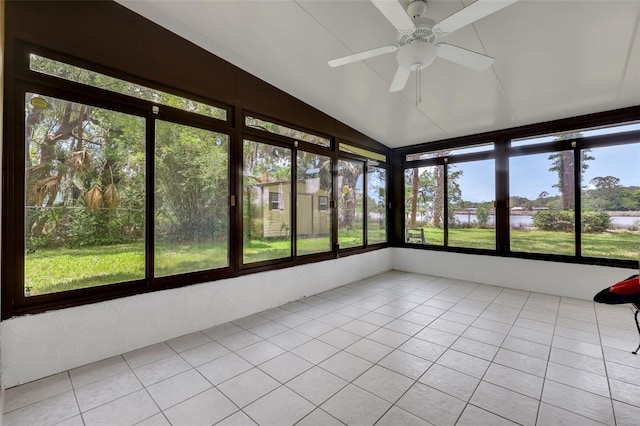 unfurnished sunroom featuring a healthy amount of sunlight, a water view, tile patterned flooring, and lofted ceiling