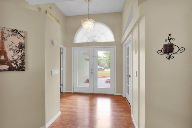 entrance foyer featuring french doors, an inviting chandelier, and wood finished floors