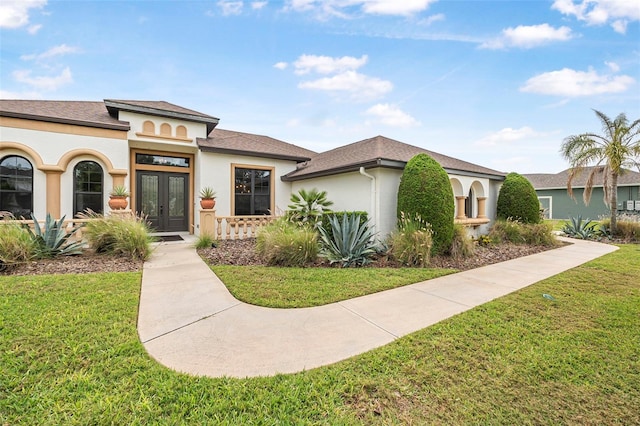 view of front facade featuring french doors, stucco siding, a shingled roof, and a front yard