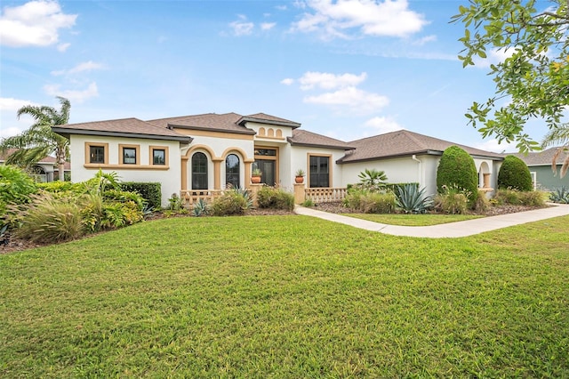 mediterranean / spanish house with a shingled roof, a front yard, and stucco siding
