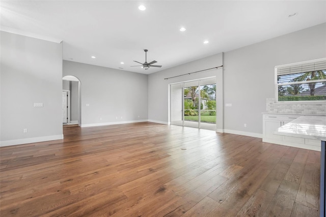 unfurnished living room featuring a ceiling fan, arched walkways, recessed lighting, and hardwood / wood-style flooring
