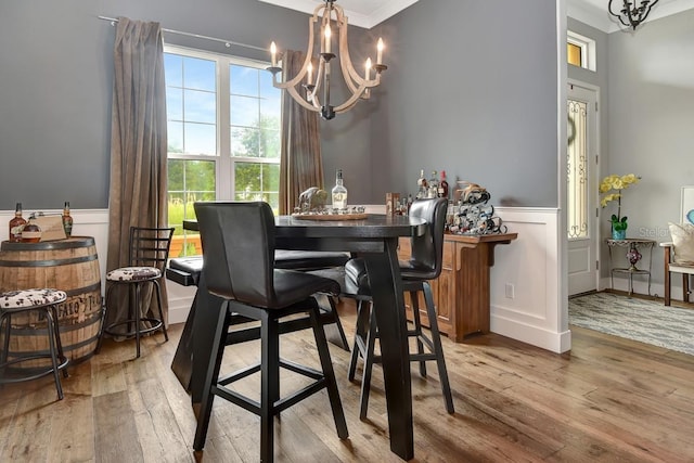 dining space with an inviting chandelier, a wainscoted wall, a decorative wall, and hardwood / wood-style flooring