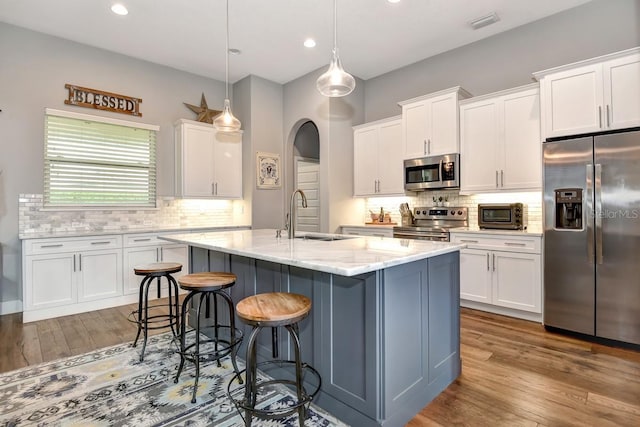 kitchen with a sink, appliances with stainless steel finishes, white cabinets, and arched walkways