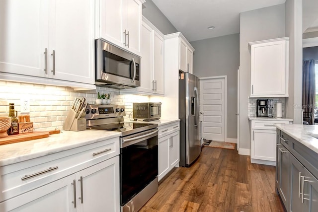 kitchen featuring dark wood-style flooring, appliances with stainless steel finishes, white cabinetry, decorative backsplash, and a toaster