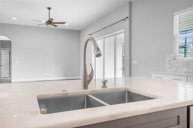 kitchen featuring ceiling fan, backsplash, arched walkways, a sink, and recessed lighting