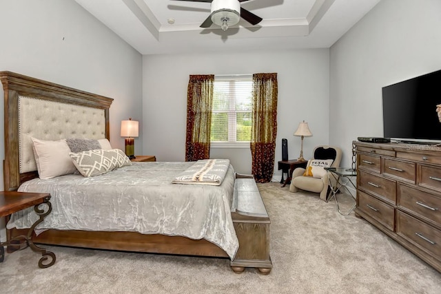 bedroom with light colored carpet, a raised ceiling, and ceiling fan
