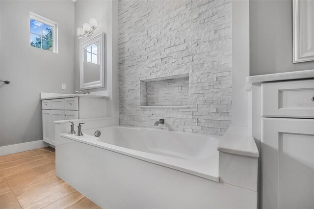 full bath featuring vanity, baseboards, a garden tub, and wood finished floors