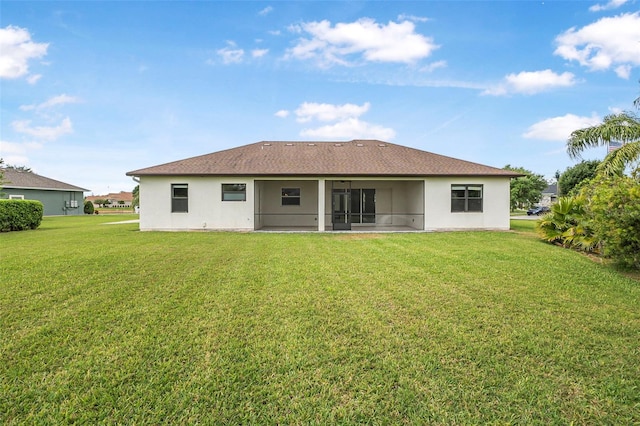 back of property with a sunroom, ceiling fan, stucco siding, and a yard