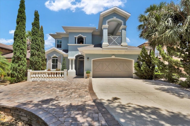 mediterranean / spanish house featuring stucco siding, concrete driveway, and a balcony