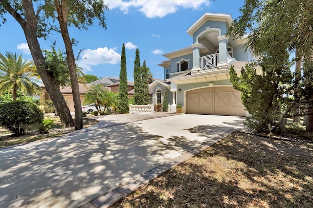 mediterranean / spanish-style home with a garage, stucco siding, a balcony, and driveway