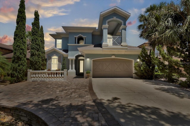 mediterranean / spanish-style home featuring a garage, driveway, a balcony, and stucco siding