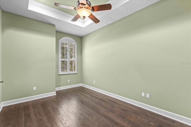 empty room with baseboards, ceiling fan, dark wood-style floors, and a raised ceiling