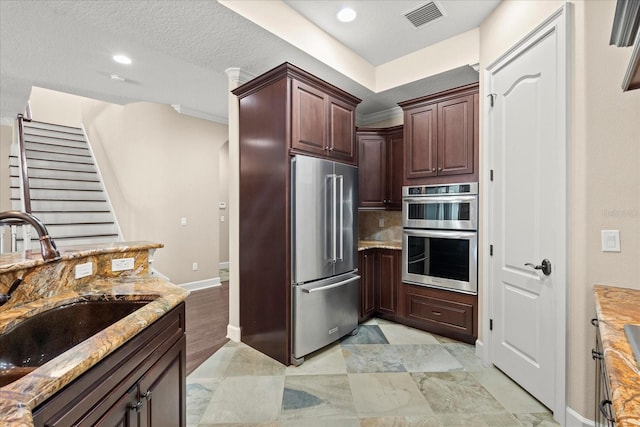 kitchen with visible vents, light stone countertops, baseboards, a sink, and appliances with stainless steel finishes