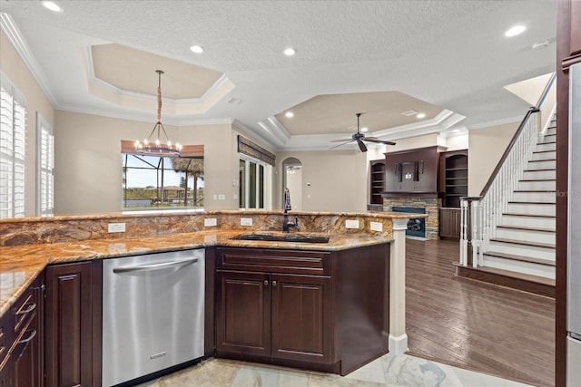 kitchen featuring stainless steel dishwasher, ornamental molding, a raised ceiling, a sink, and ceiling fan with notable chandelier