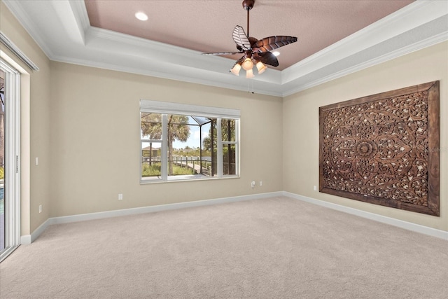 unfurnished room with crown molding, a ceiling fan, a tray ceiling, and carpet floors