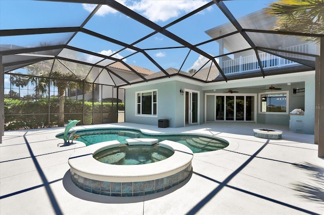 view of swimming pool featuring a ceiling fan, a pool with connected hot tub, glass enclosure, an outdoor fire pit, and a patio