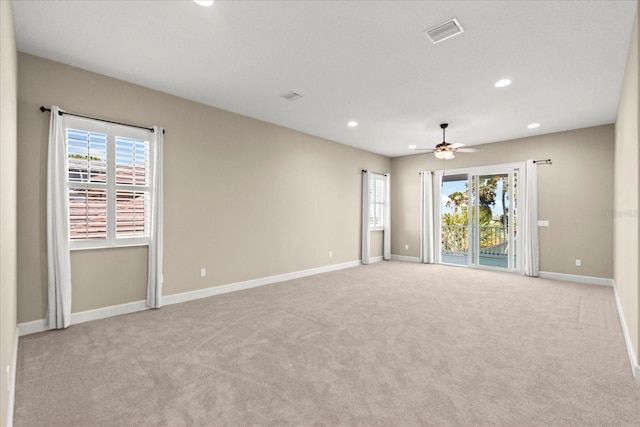 empty room featuring a healthy amount of sunlight, ceiling fan, light colored carpet, and visible vents