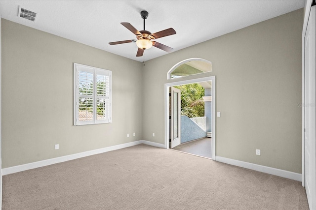 carpeted empty room with ceiling fan, visible vents, and baseboards