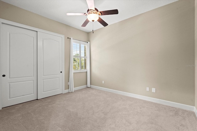 unfurnished bedroom with carpet flooring, baseboards, ceiling fan, and a closet