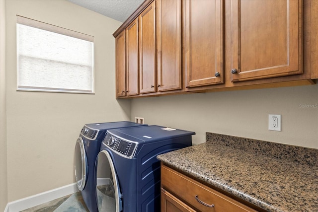 laundry area featuring baseboards, cabinet space, and independent washer and dryer