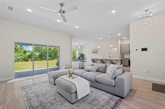 living room featuring baseboards, ceiling fan, light wood-style flooring, and visible vents