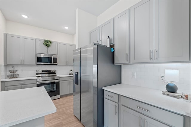 kitchen with decorative backsplash, gray cabinets, and appliances with stainless steel finishes