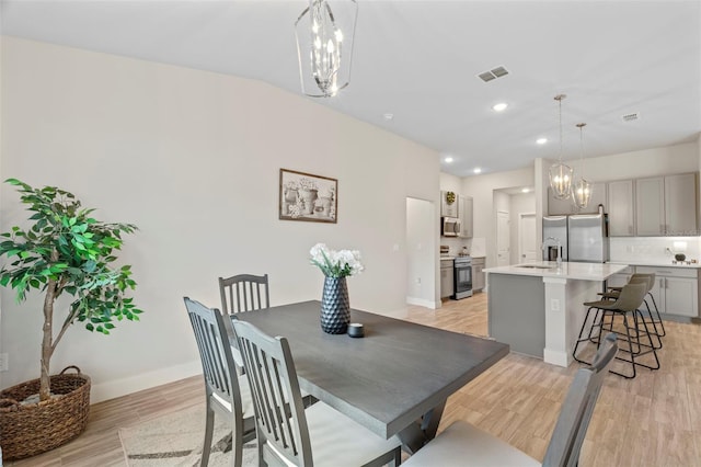 dining space featuring an inviting chandelier, baseboards, light wood-style flooring, and visible vents